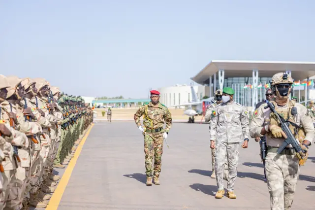 Le général Assimi Goita, président de la transition au Mali, en tenue militaire et béret vert, passe en revue les troupes lors d'une cérémonie officielle.