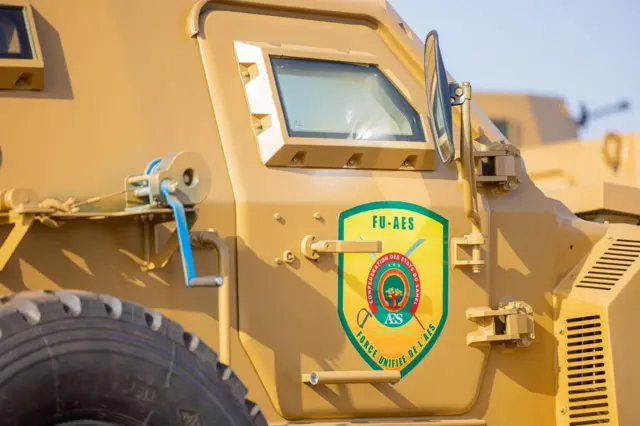 Un véhicule militaire jaune portant l'inscription 'FU-AES' sur une affiche.
