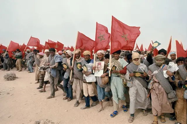 Des civils marocains brandissent des drapeaux nationaux, des exemplaires du Coran et des portraits du roi Hassan II lors de la Marche verte de novembre 1975, au cours de laquelle Rabat a fait pression sur l'Espagne pour qu'elle abandonne le Sahara occidental.